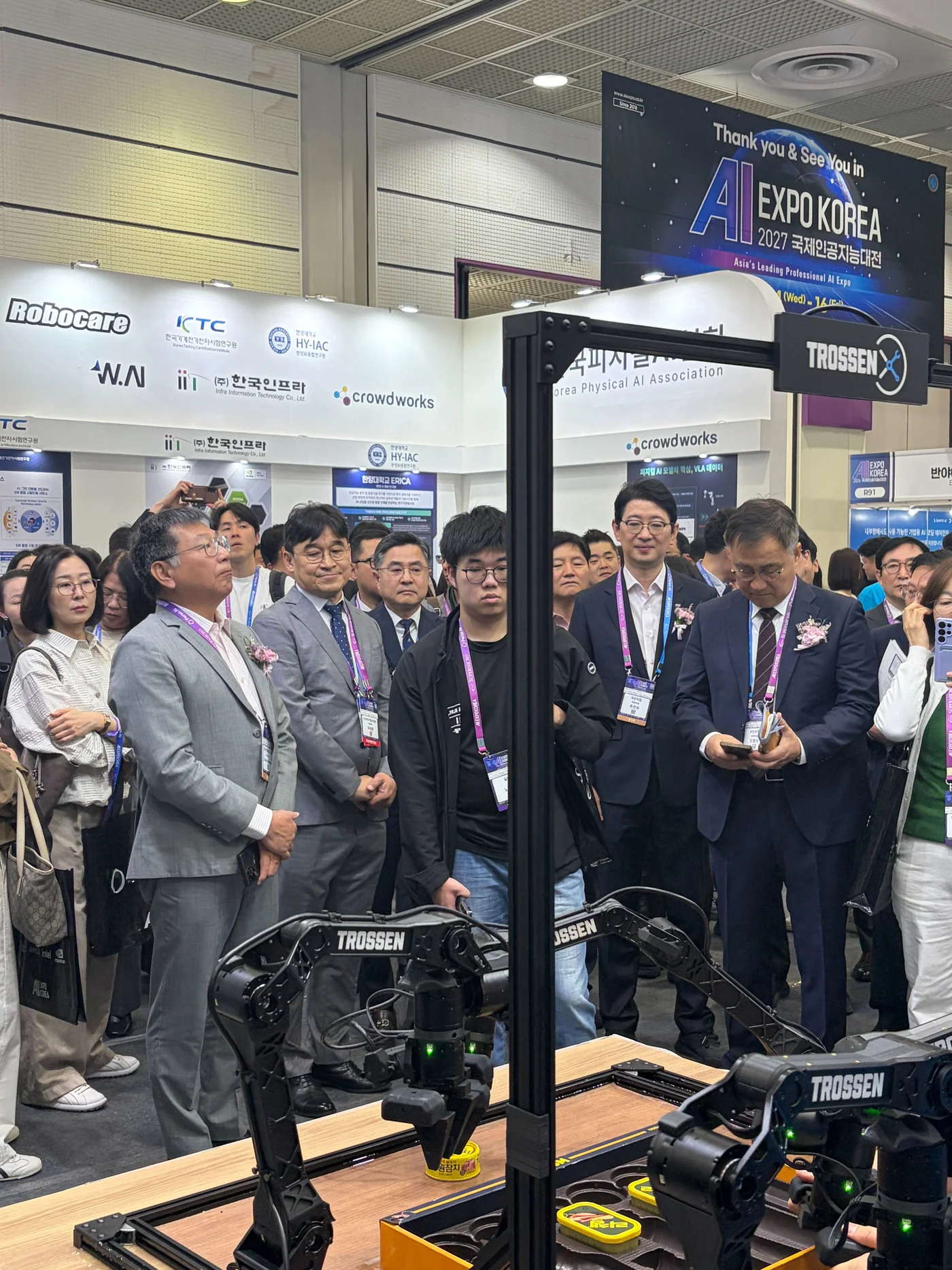 Visitors watching a robotic arm demonstration at an exhibition
